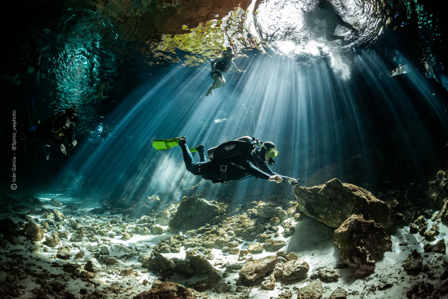 Two divers under a low limestone ceiling in Dos Ojos