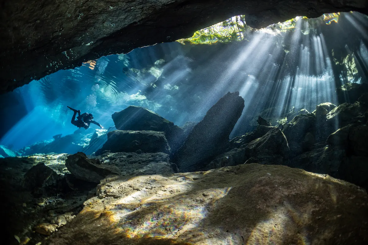 Diver near sunlit boulders in Kukulcan cenote