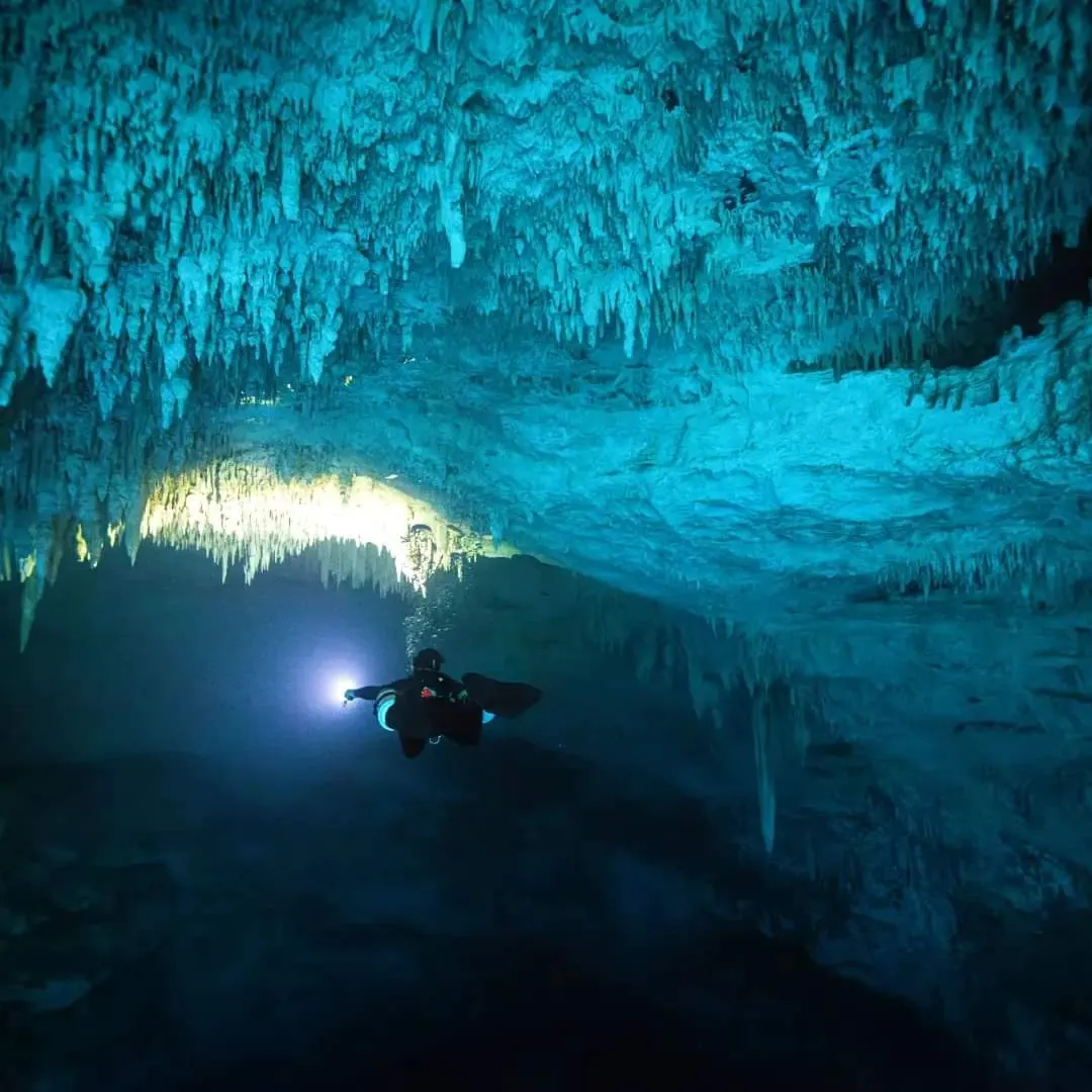 Sidemount diver entering a blue cave passage